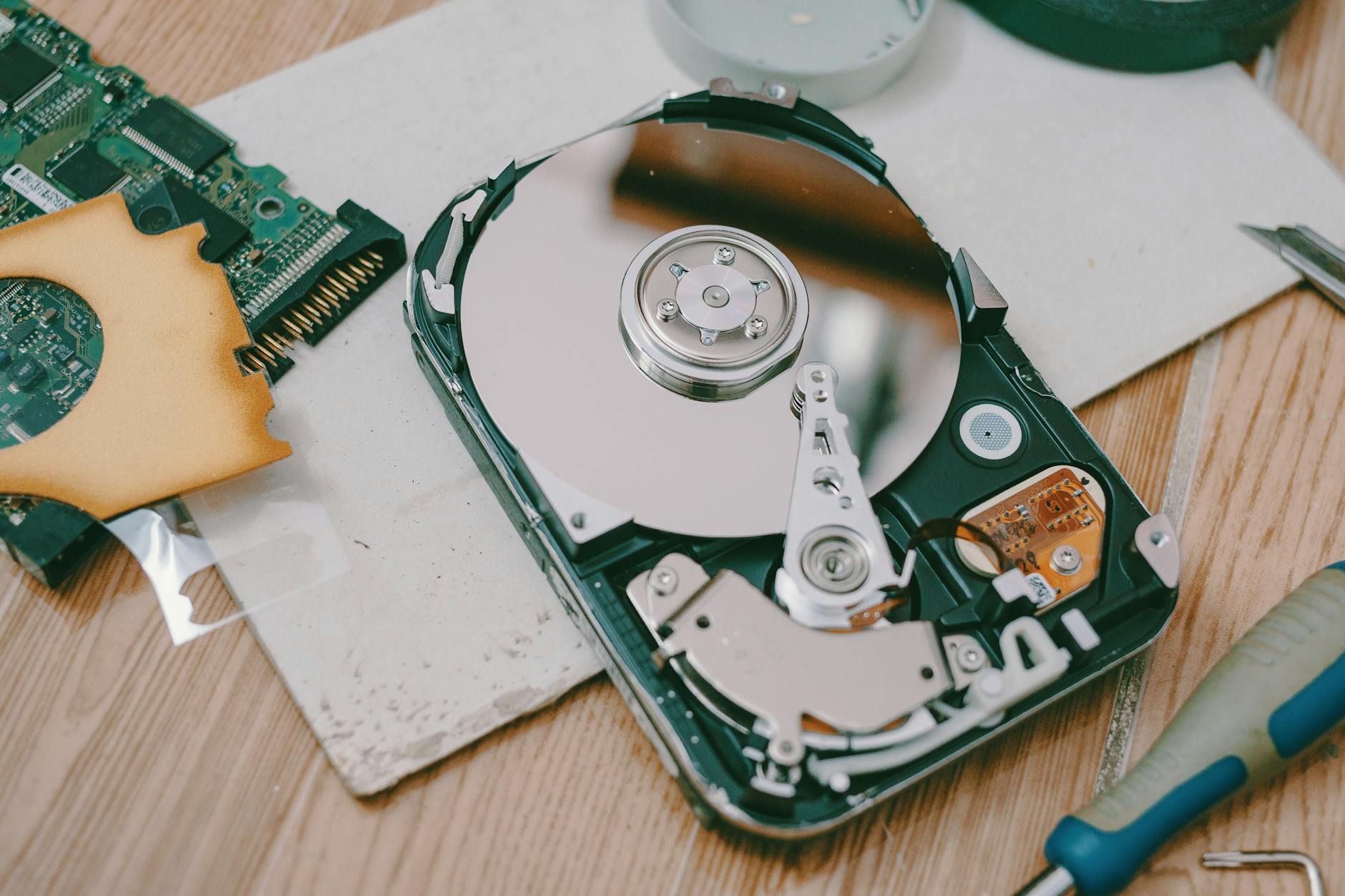 Rozebrany dysk twardy HDD z widocznymi talerzami na drewnianym stole